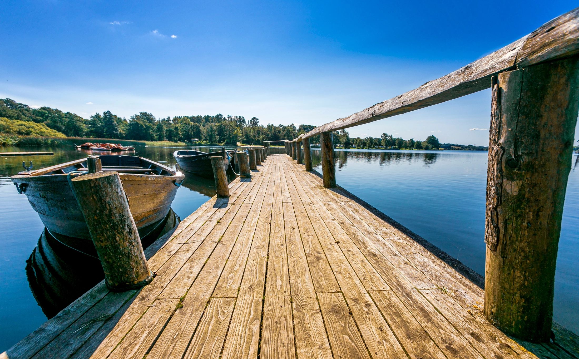Wooden bridge in a lake with rowing boats moored